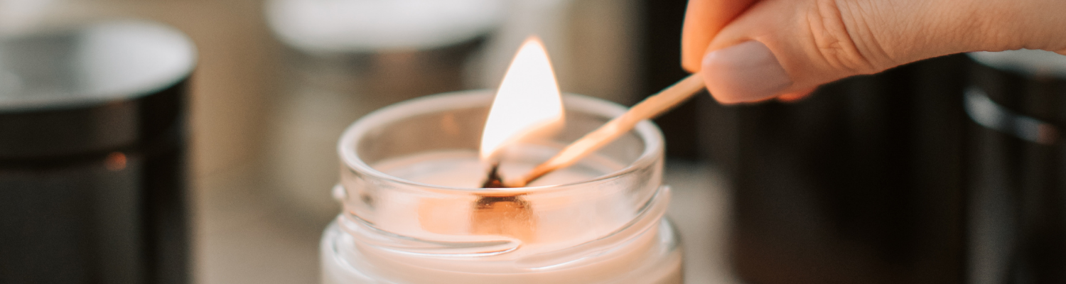 Kerze im Glas, die mit einem Streichholz entzündet wird – stimmungsvolles Bild für das Flying Wish Paper als besinnliche Weihnachtsgeschenk-Idee für Hundehalter.