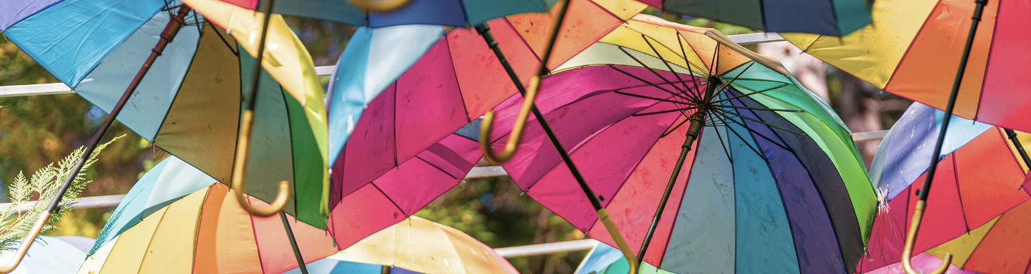 Viele bunte Regenschirme dicht nebeneinander von seitlich unten fotografiert