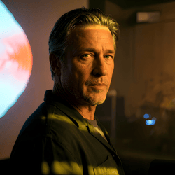 Jonas Danling (2021). Ein älterer Mann mit Bart und ernstem Blick in rotem Licht. Er wirkt nachdenklich und gefasst, als jemand, der seine Vergangenheit akzeptiert hat.